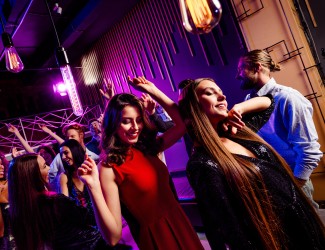 Photo d'une soirée entre étudiants qui dansent en boîte de nuit, il y a plusieurs femmes en premier plan et un groupe en second plan