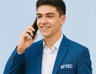 jeune homme de 18 ans portant un téléphone à l'oreille, il est en train de passer un appel. Il porte un costard bleu AFTEC