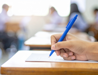 Main tenant un crayon bleu lors d’un examen écrit dans une salle de classe