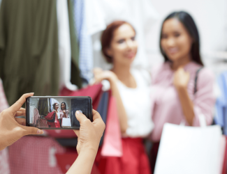 Deux femmes dans un magasin posant pour une photo avec des sacs de shopping à la main