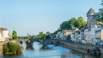 Photo d'un lieu emblématique de la ville de Laval, un pont au dessus d'un canal avec la ville historique autour.