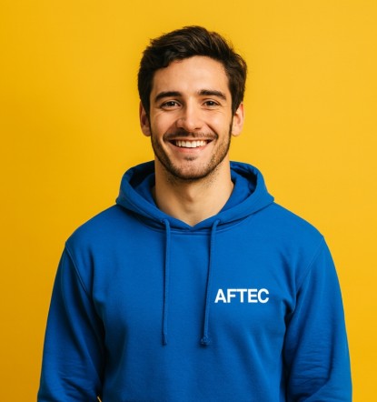 jeune homme de 24 ans portant un sweat à capuche bleu avec le logo AFTEC sur un fond jaune uni