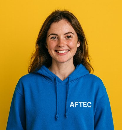jeune étudiante de 25 ans portant un sweat à capuche bleu avec le logo AFTEC sur un fond jaune