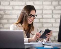Une jeune femme qui travaille sur sa calculatrice, dans son bureau