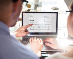 Deux collaborateurs consultent une facture électronique sur un ordinateur portable