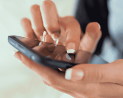 une femme tenant un téléphone et cliquant avec son doigt sur l'écran tactile.