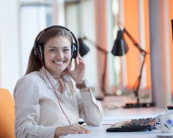femme avec casque téléphone à son bureau devant un ordinateur