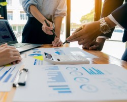 trois personnes travaillant autour d'une table sur laquelle se trouve des documents avec des statistiques