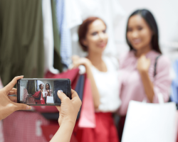 Deux femmes dans un magasin posant pour une photo avec des sacs de shopping à la main