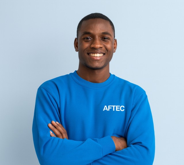 jeune étudiant de 20 ans portant un pull bleu avec le logo AFTEC sur un fond bleu